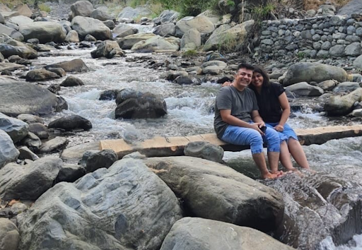 Niti and her husband posing for a photo by a waterfall